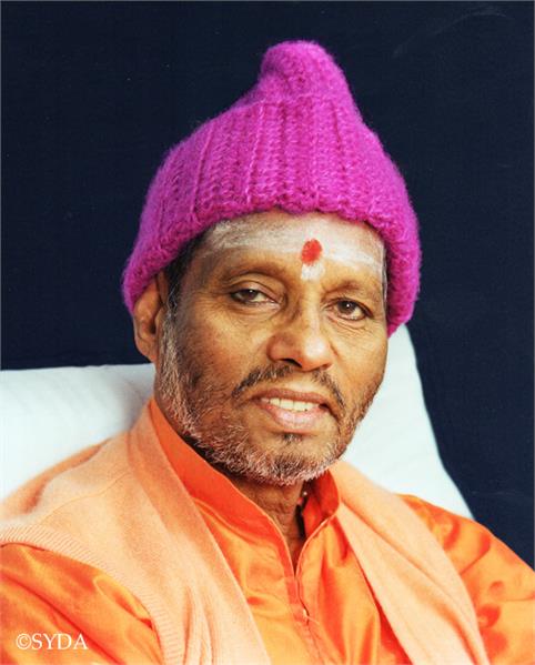 Close up of Baba in orange robes and a pink hat