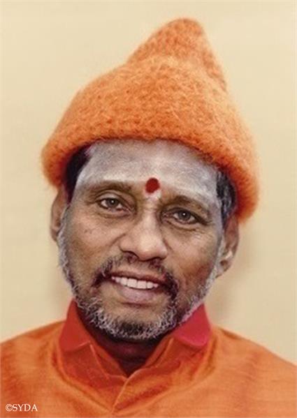 Close up photo of baba in orange robes and orange hat against a beige background