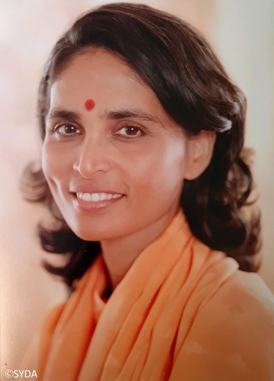 Close up of Gurumayi smiling against a beige background