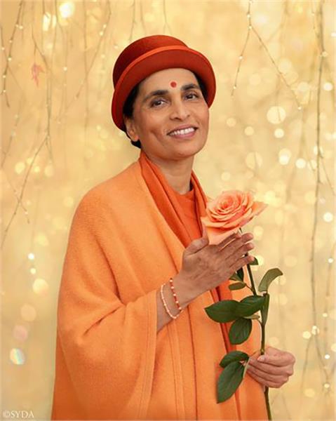 Gurumayi holding exquisite coral rose at the culmination of Sweet Surprise 2019.