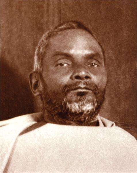 Close up of Nitynanda in white shawl with brown background